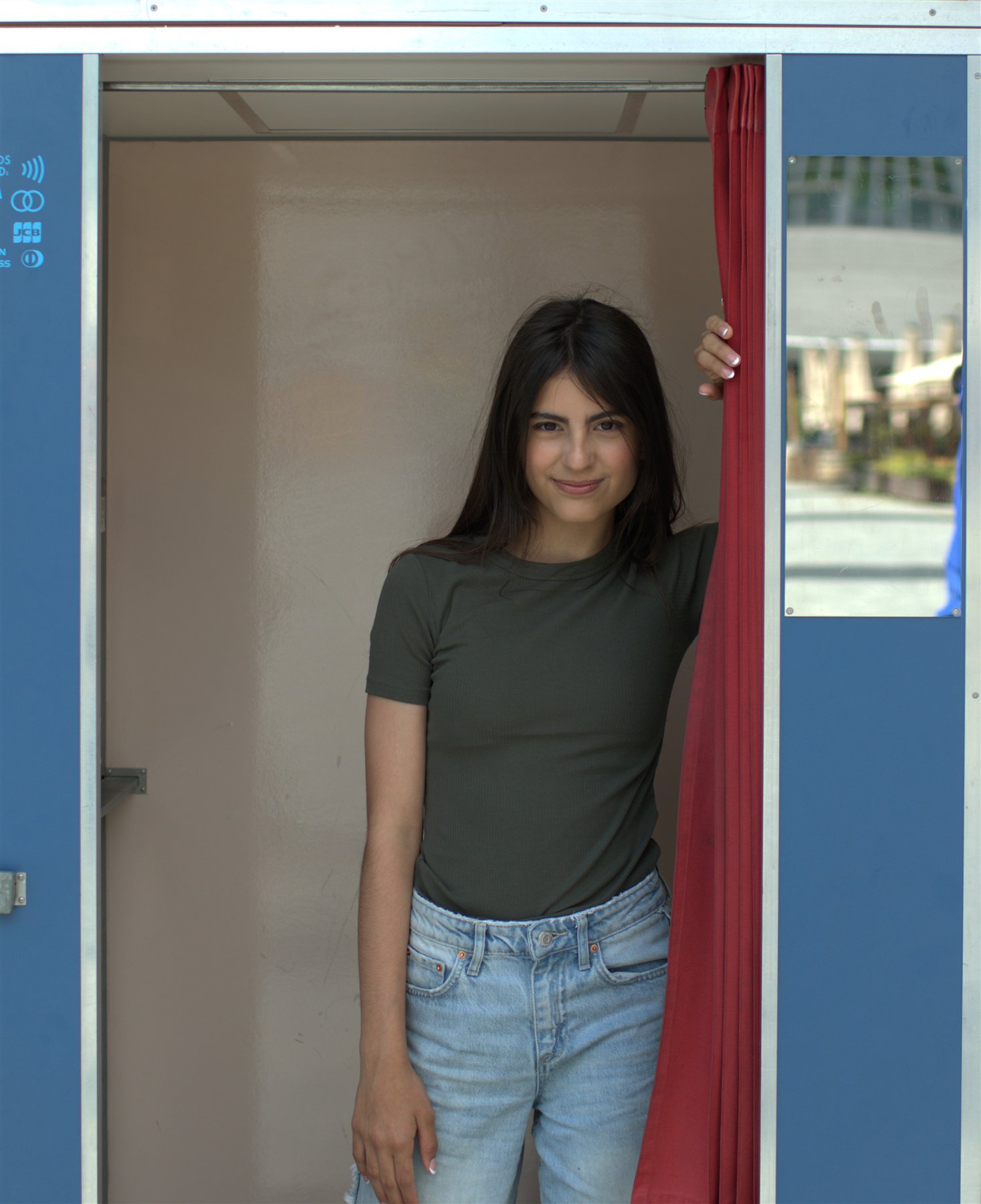 Creative portrait framed by a blue booth with a red curtain