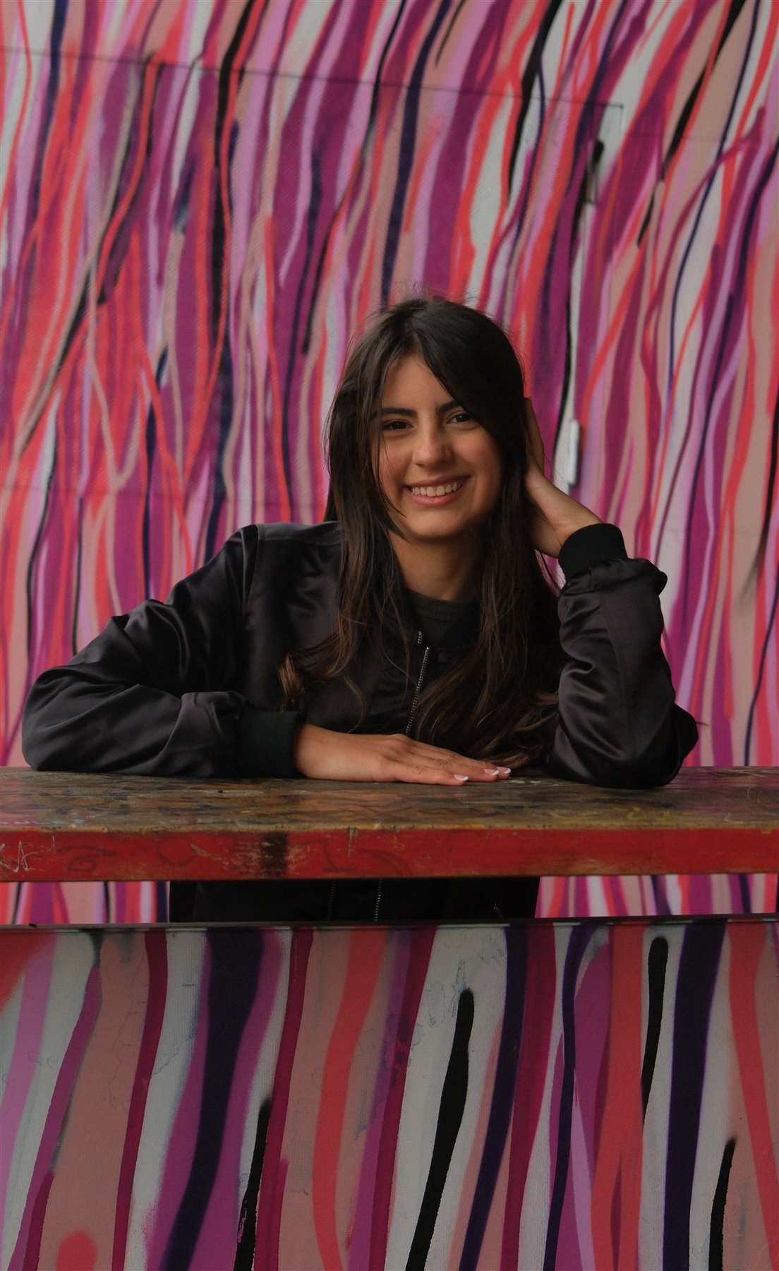 Creative portrait in Berlin against a vivid pink graphic wall