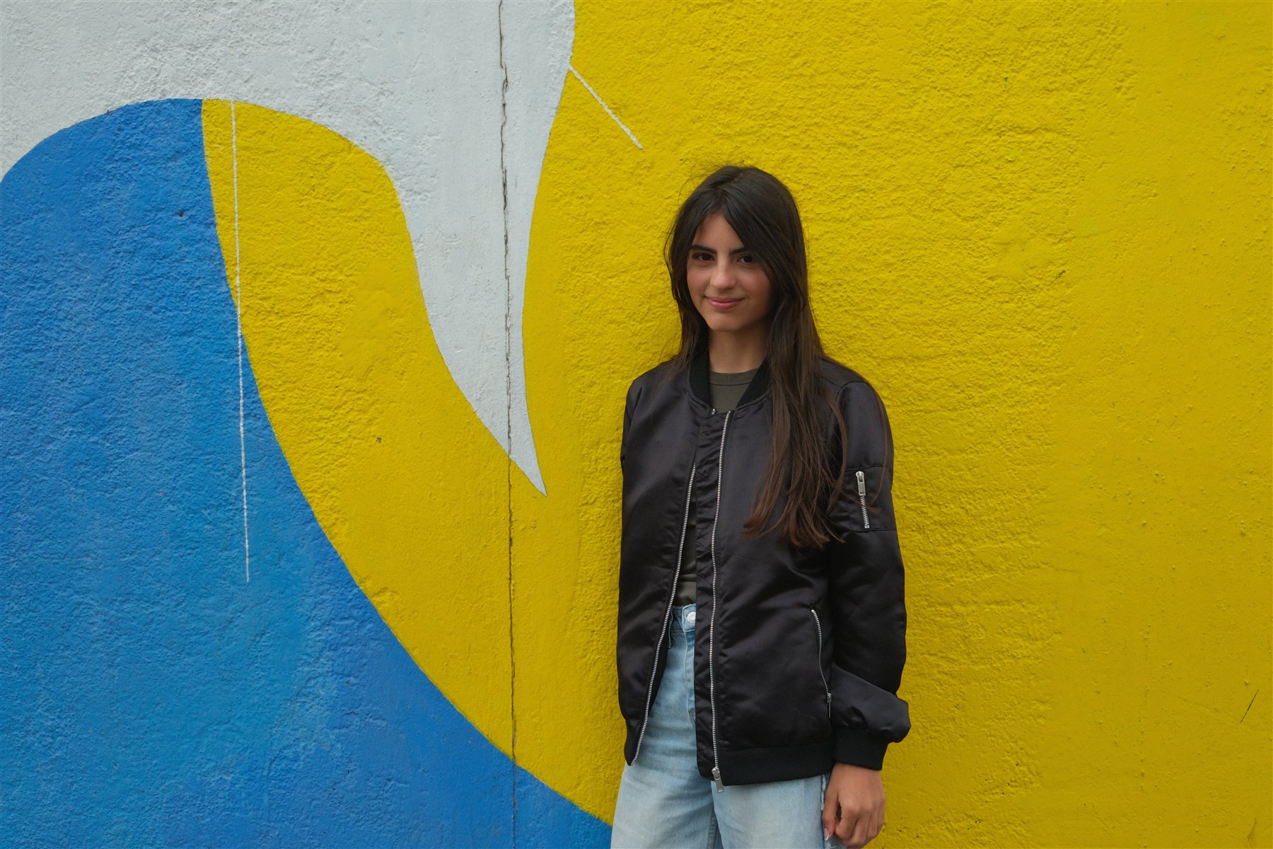 Full-length creative portrait against a yellow and blue wall in Berlin