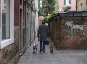 A man with 2 small dogs match in coincidence to the dog graffiti