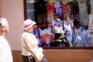 Window display mannequin have the same hat like the woman passing by
