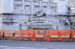 Construction crew performing street work next to a statue of a roman chatechter