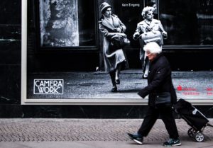 An old woman is walking next to an old woman poster